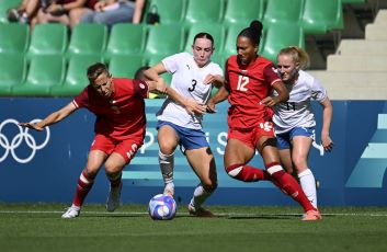 Women's football teams tackling a ball in the field