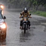 A man riding a bike amidst heavy rainfall in New Delhi